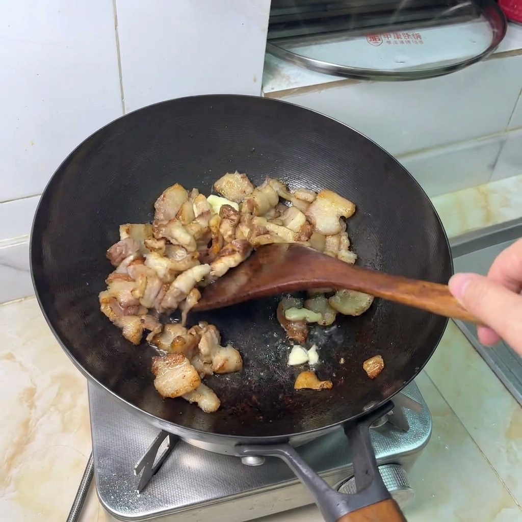 Gousses dail écrasées sautées avec les morceaux de porc dorés.
