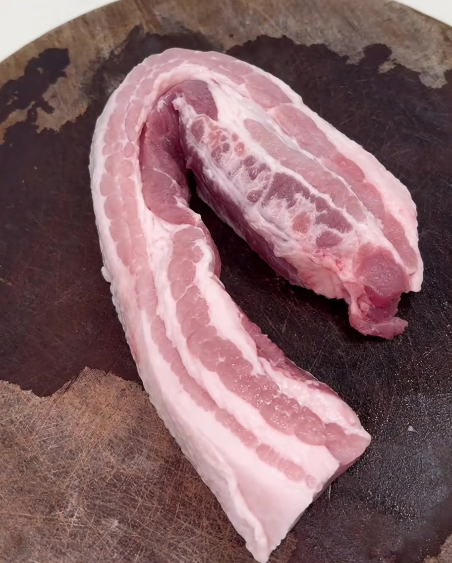 Tranches de poitrine de porc en train de dorer dans un wok chaud.