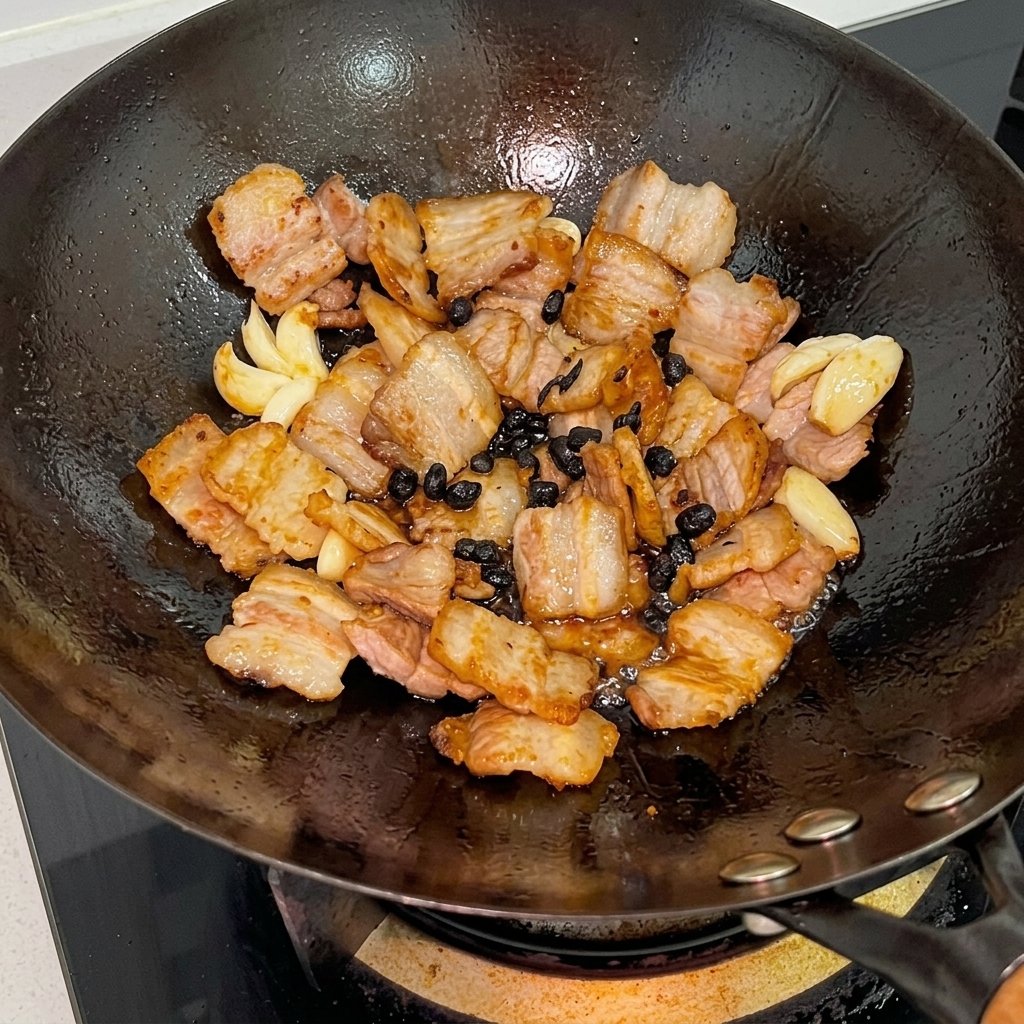 Sauce huître et sauces soja versées sur le mélange de porc dans le wok.