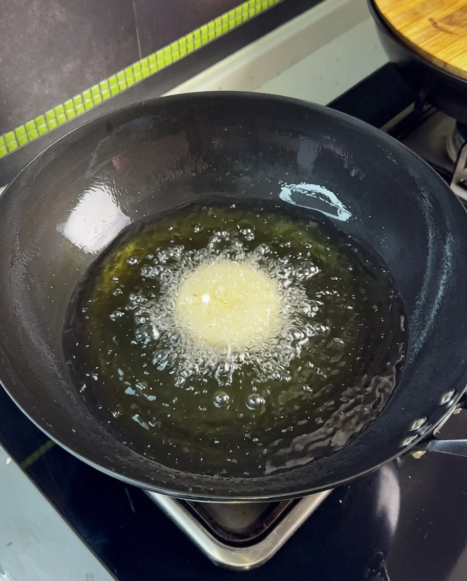 Une tranche de poitrine de porc plongée dans lhuile chaude dun wok, créant des bulles.