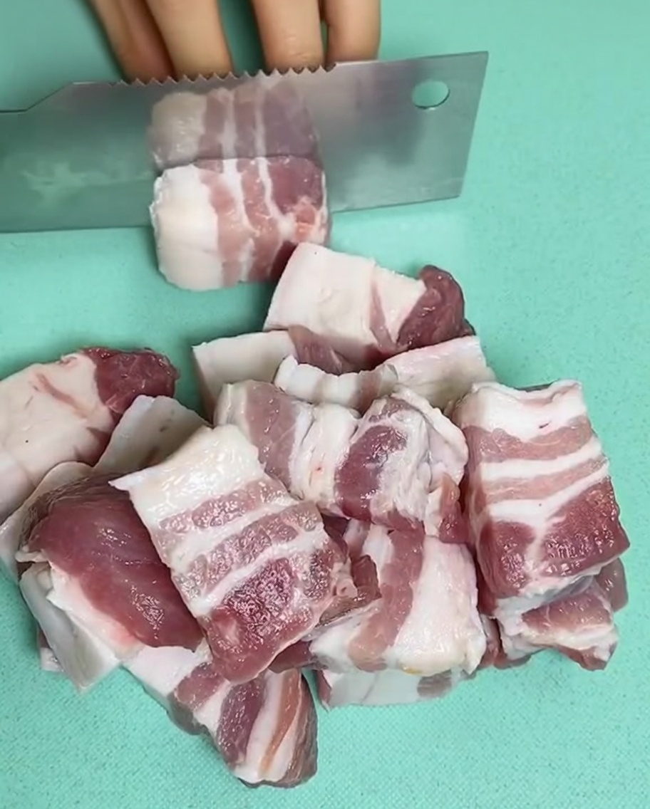 Morceaux de poitrine de porc crus dans une casserole remplie deau froide, avec du gingembre et du vin de cuisine.