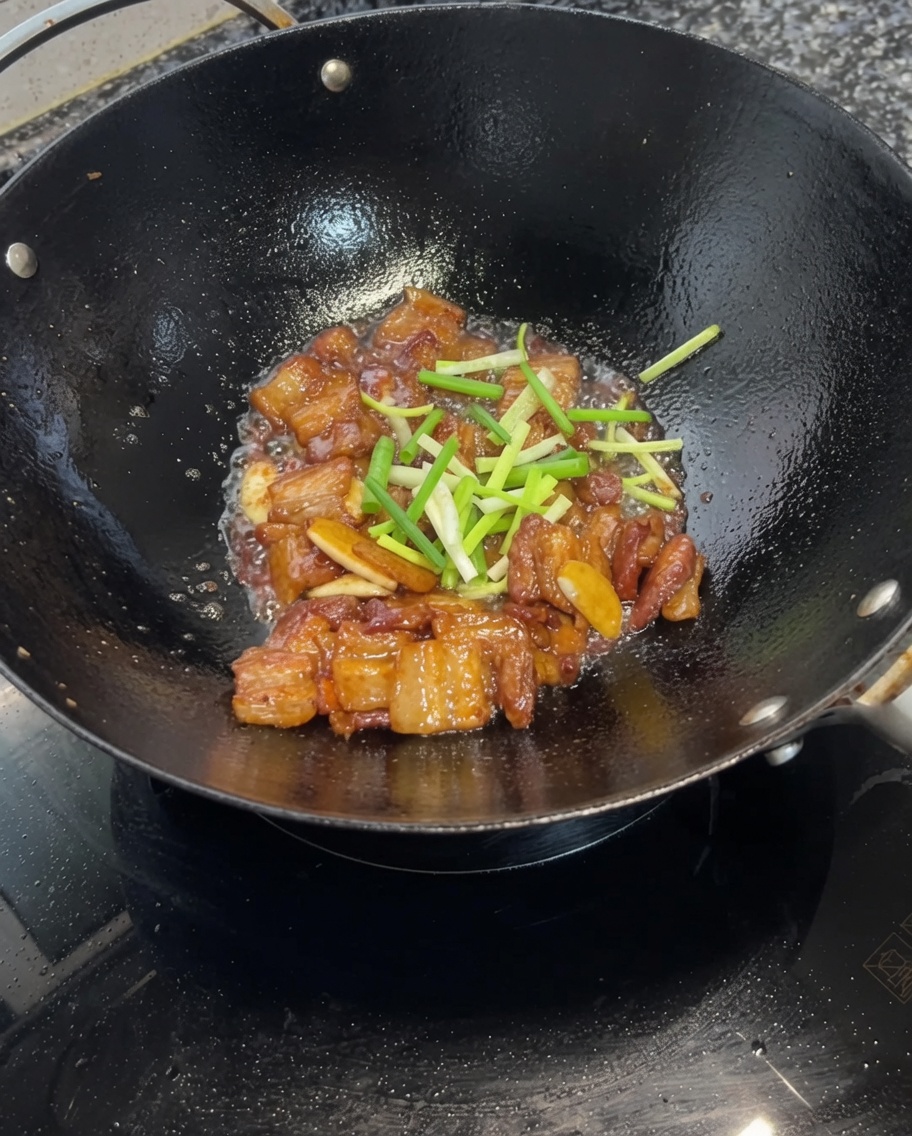 Oignons nouveaux hachés mélangés avec le porc laqué à la sauce soja dans le wok.