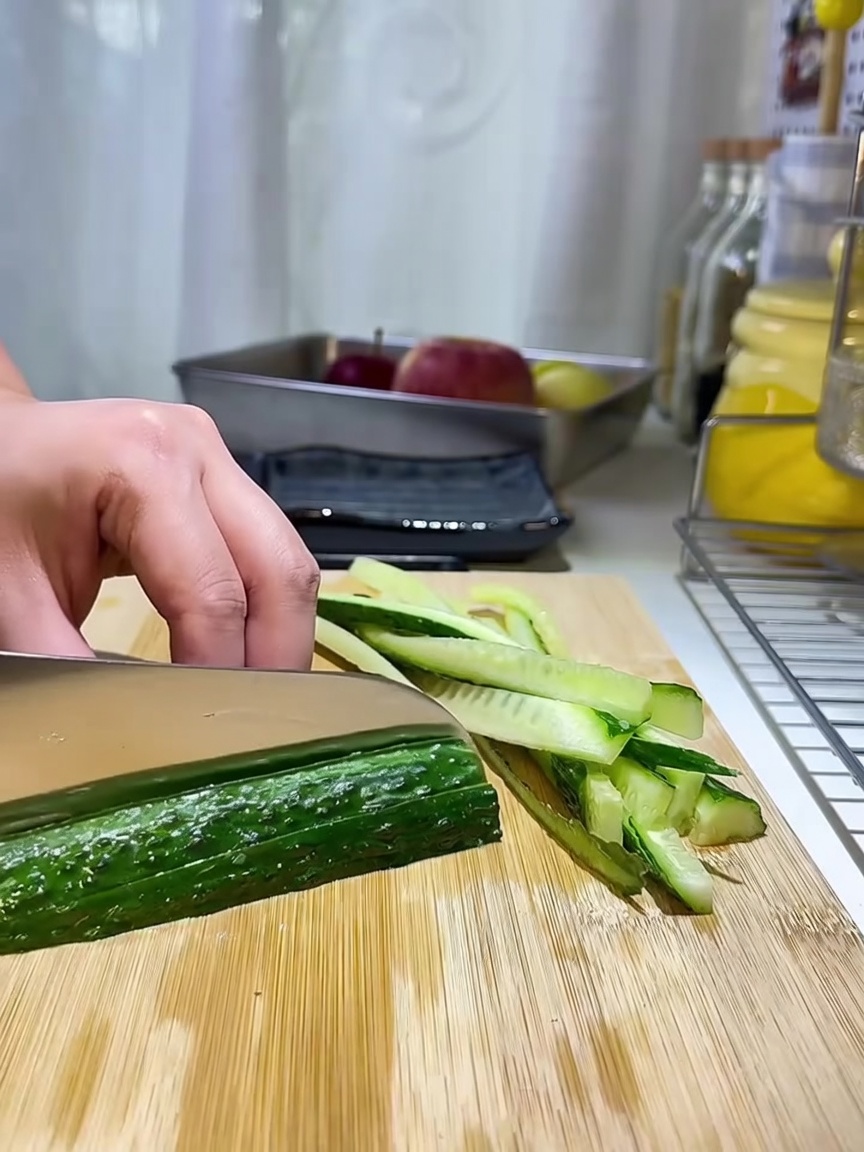 Lanières de concombre soigneusement disposées sur une planche à découper en bois.
