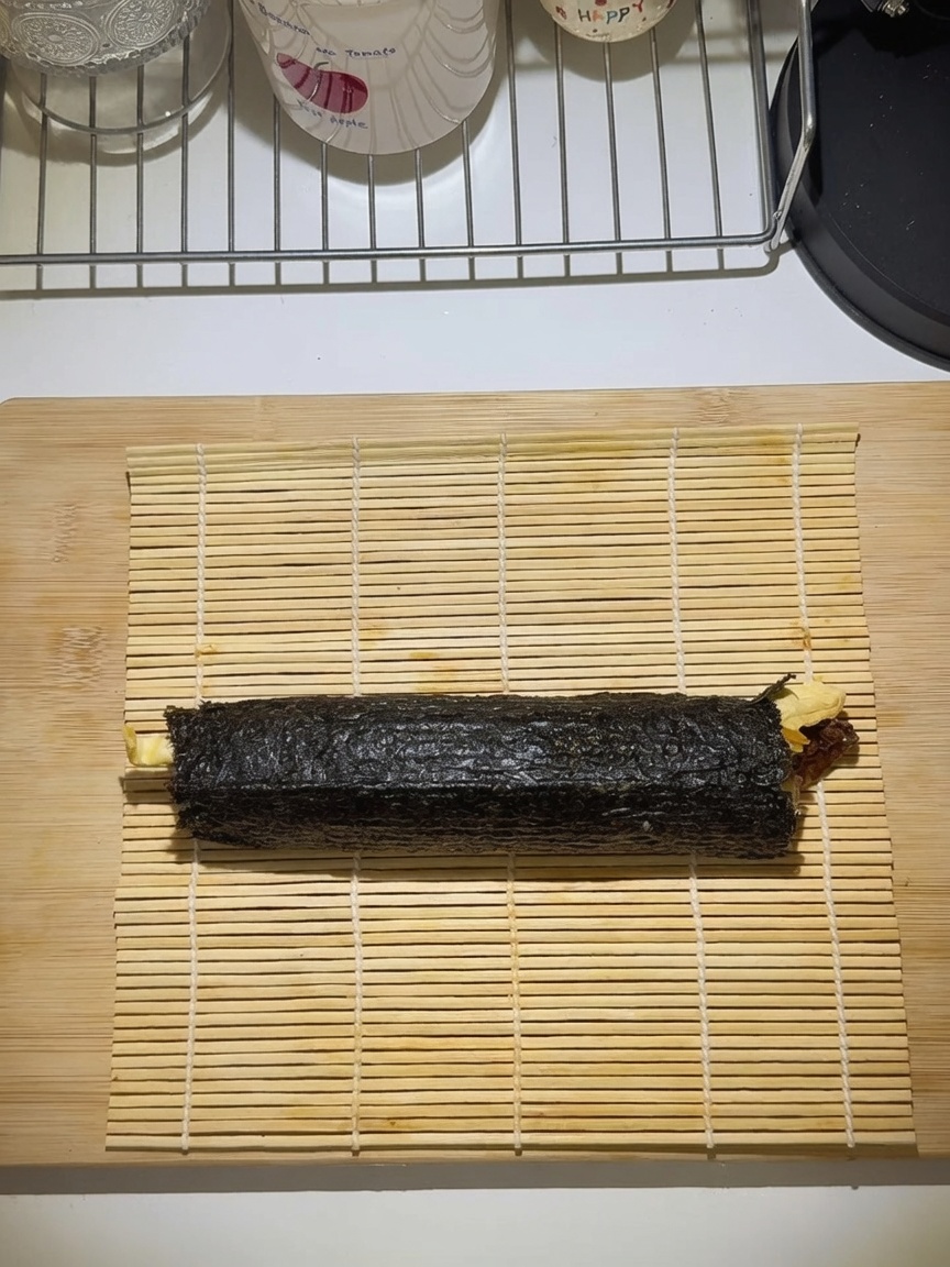 Gimbap étroitement roulé sur un tapis de bambou.