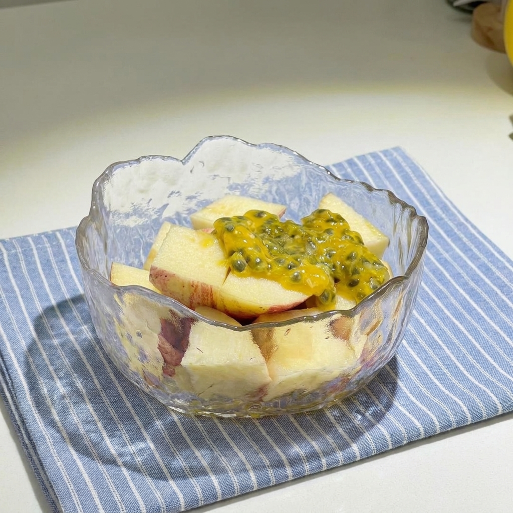Bol en verre rempli de dés de pommes rouges, surmontés de pulpe jaune de fruit de la passion et arrosés de miel.
