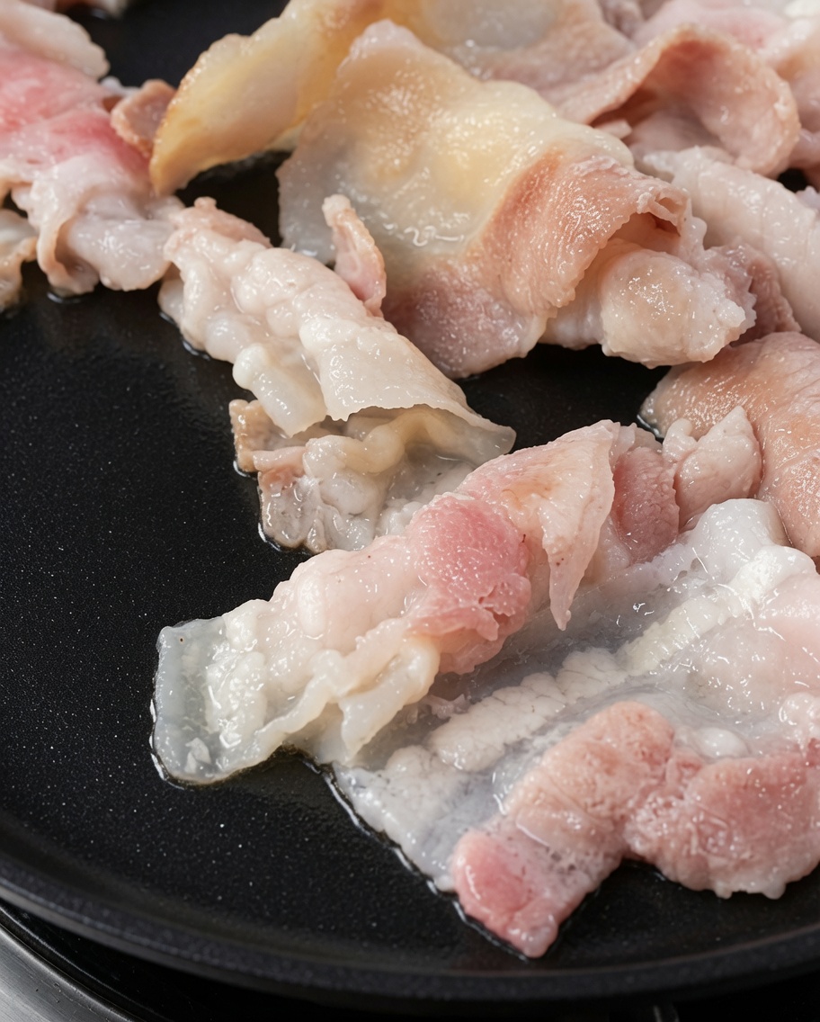Tranches de poitrine de porc grillées et dorées sur une plaque chaude.