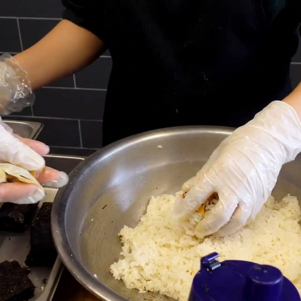 Une boulette de riz gluant tout juste façonnée avec un petit carré dalgue séchée pressé sur sa surface.