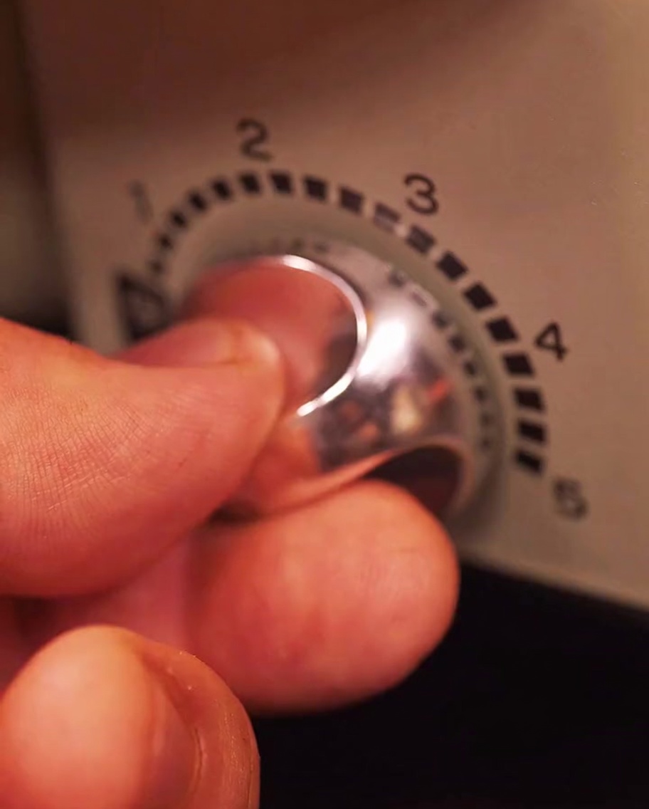 Main ajustant le bouton de température sur un gril électrique pour augmenter lintensité.