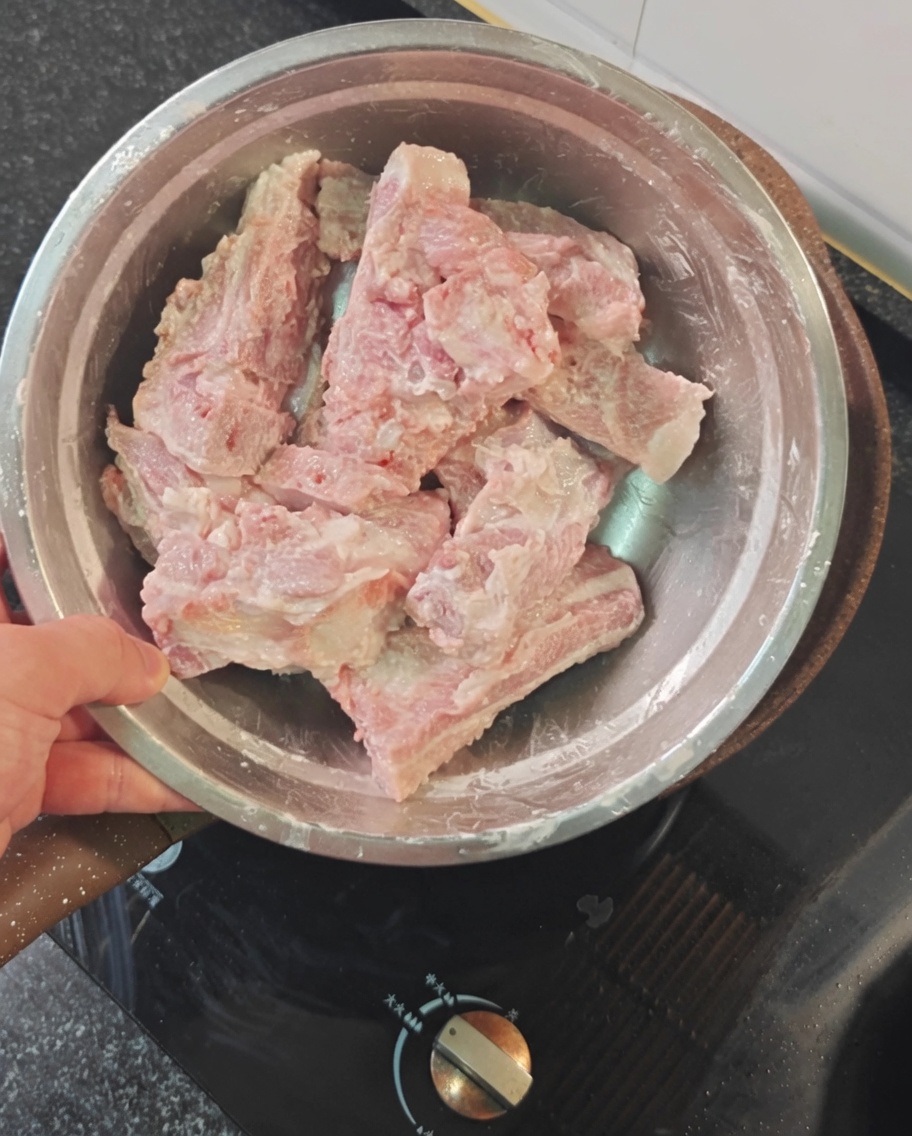 Travers de porc crus enrobés de fécule rouge dans un bol en métal.