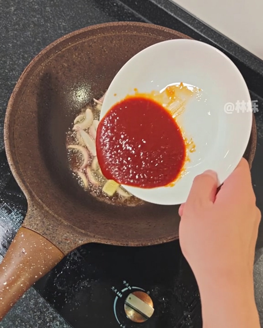Sauce épicée versée dans une poêle avec les aromates sautés.