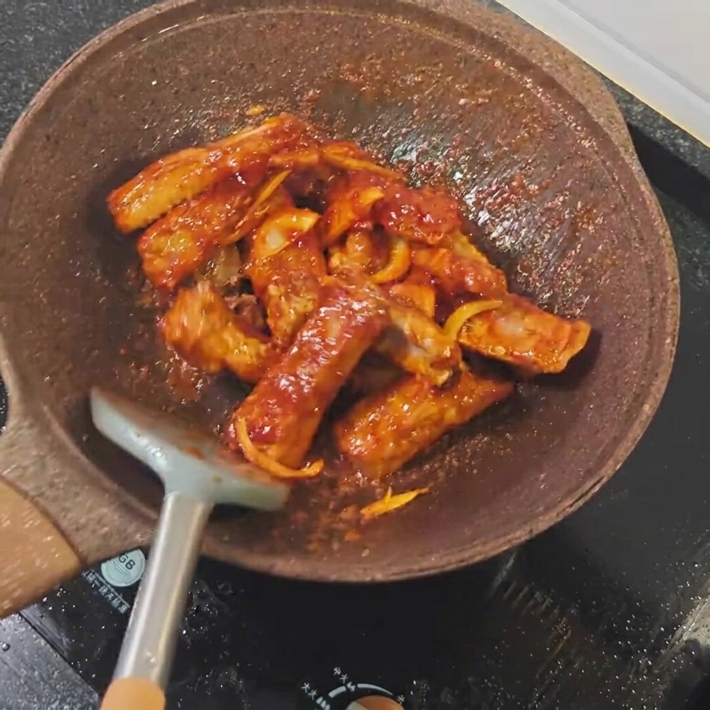 Sauce soja claire versée sur les travers de porc dans une poêle.