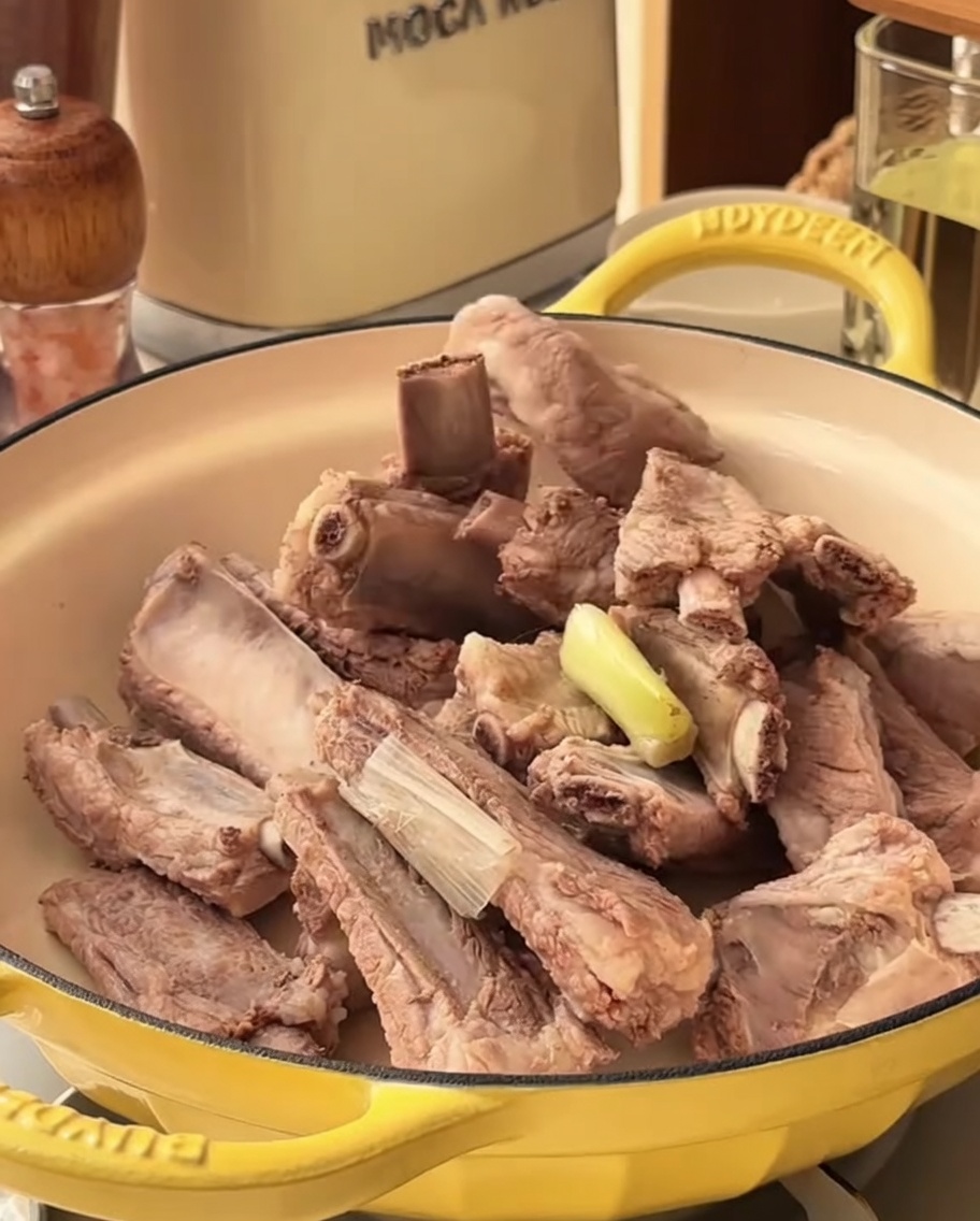 La marinade épicée est versée sur les travers de porc blanchis dans une marmite.