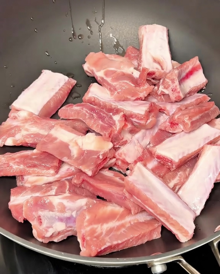 Travers de porc mijotant dans une casserole deau avec des aromates.