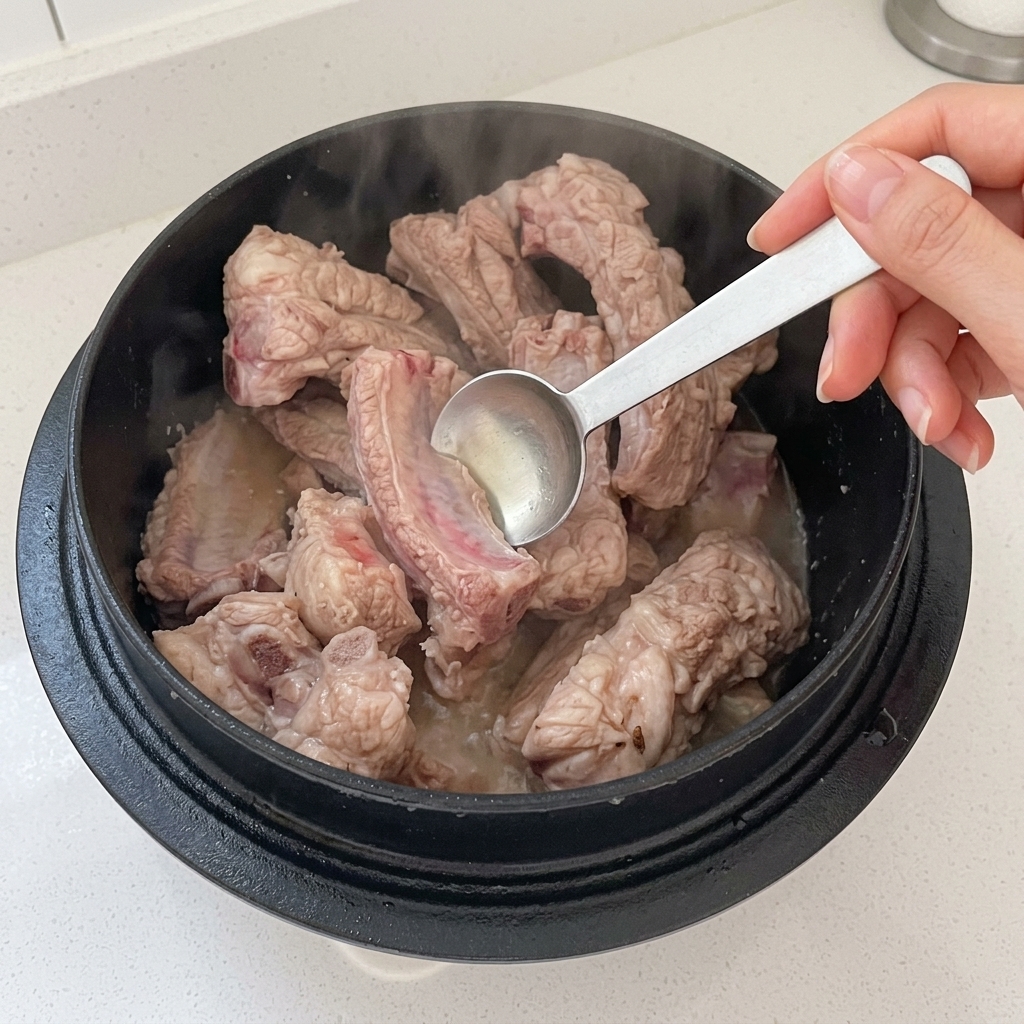 Ajout du vinaigre dans la marmite contenant les travers de porc.