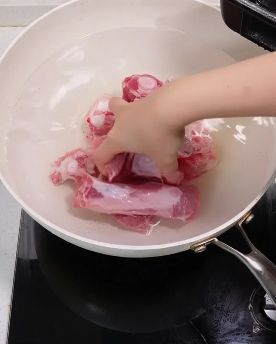 Travers de porc bouillant dans une marmite avec des oignons verts et des tranches de gingembre.