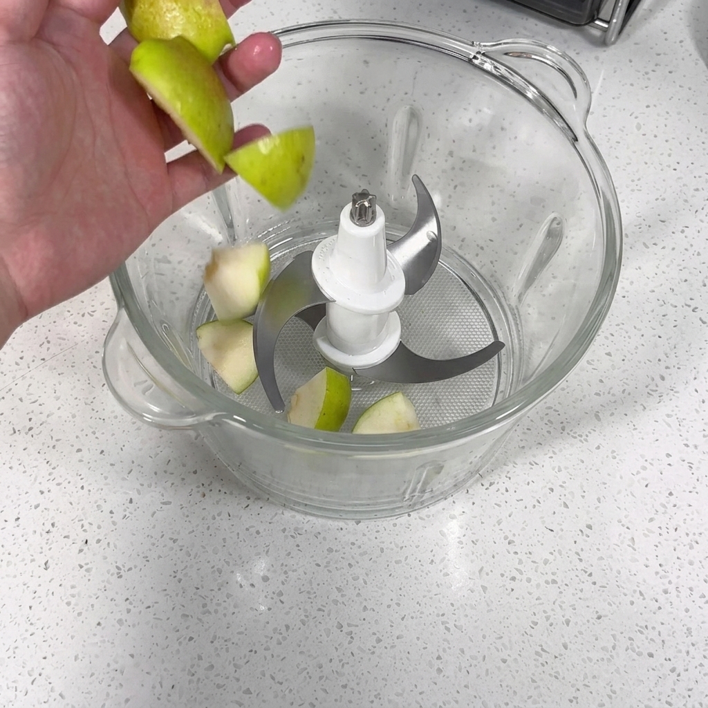 Un robot culinaire mixant des morceaux de pomme, de poire, dail et doignon en une purée.