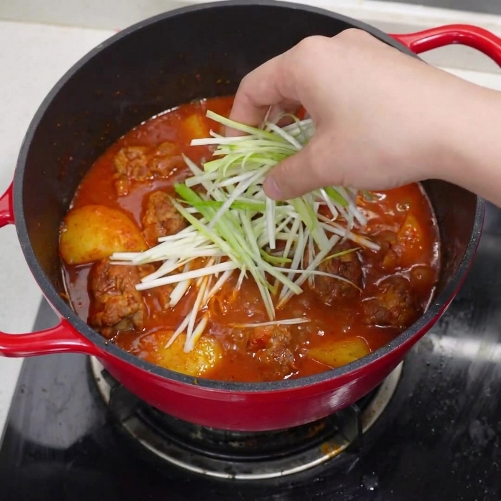 La cocotte terminée, décorée doignons verts, de piments rouges et de poivre noir.