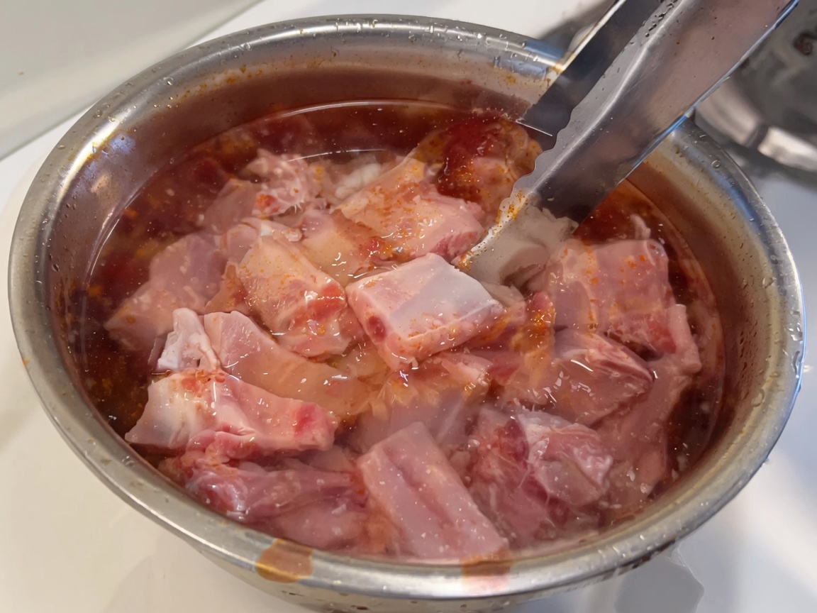 Travers de porc crus et frais immergés dans un bol deau claire.