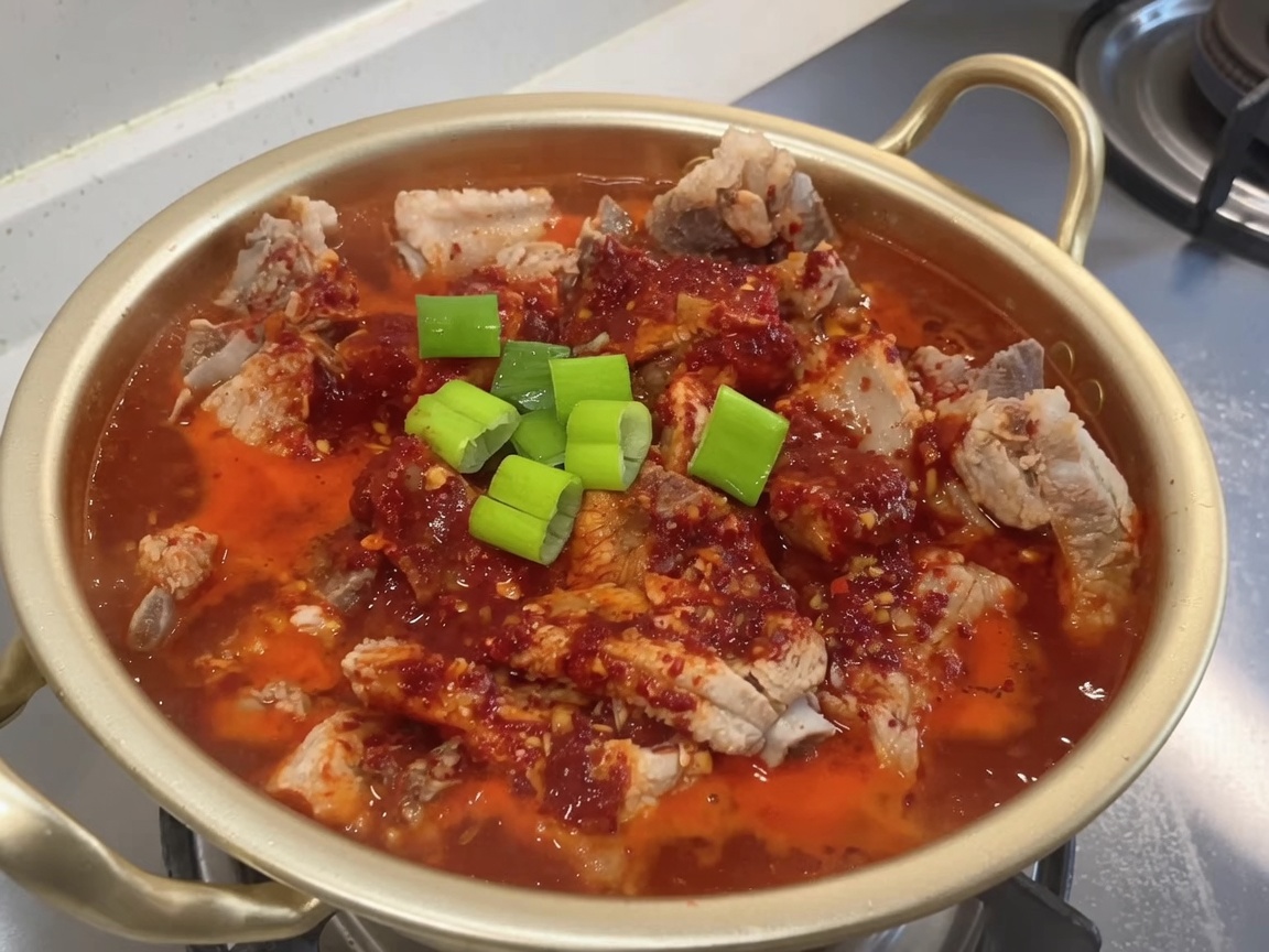 Casserole de côtes braisées garnie doignons verts frais hachés.