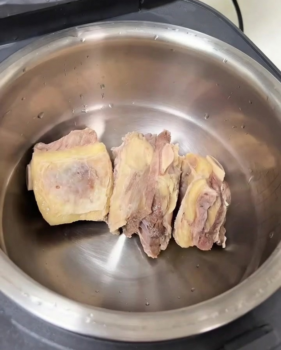 La cuve intérieure dun cuiseur de riz contenant des côtes de bœuf nettoyées et divers aromates.