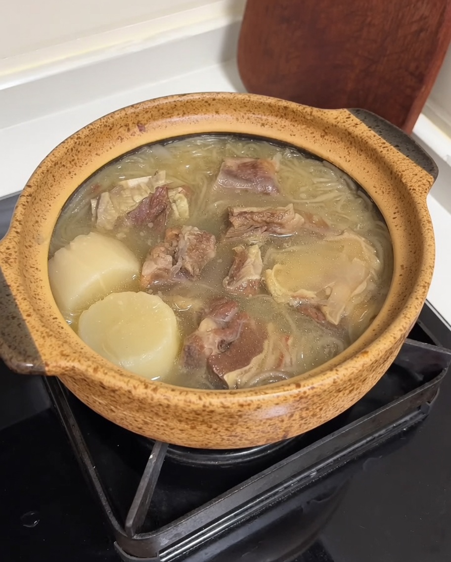 Un pot en céramique rempli de soupe de bœuf, garni de lanières dœufs jaune vif et doignons verts tranchés vibrants.