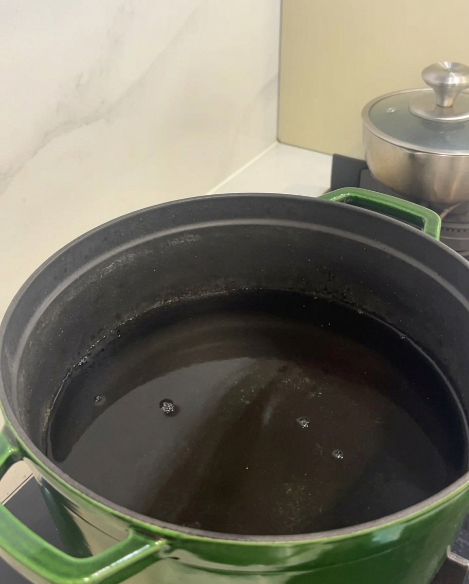 Morceaux de bœuf dans une grande cocotte verte remplie deau froide.