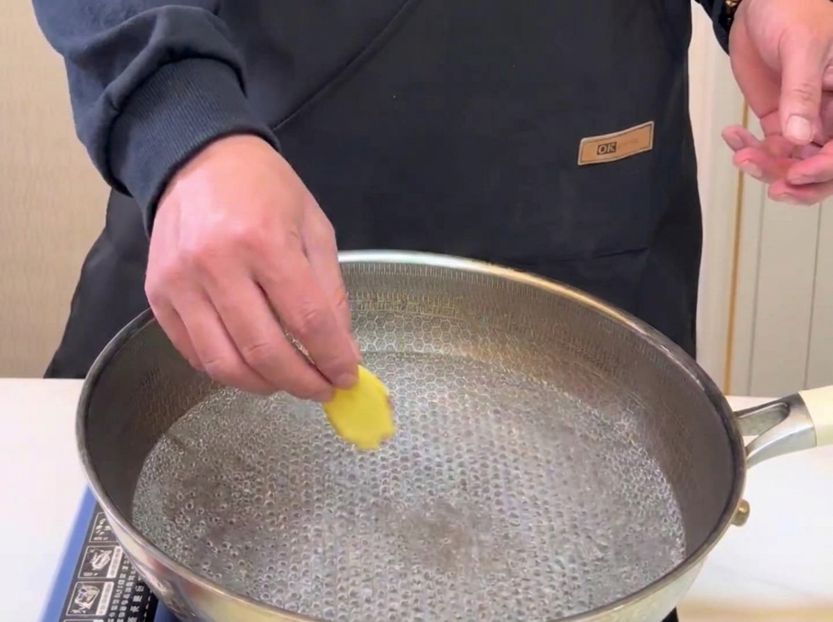 Des tranches de gingembre plongées dans une casserole deau bouillante pour le blanchiment.