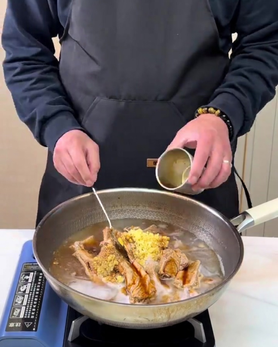 Jus de poire fraîchement préparé versé depuis un petit récipient en métal dans une casserole de cuisson avec les côtes et les assaisonnements.
