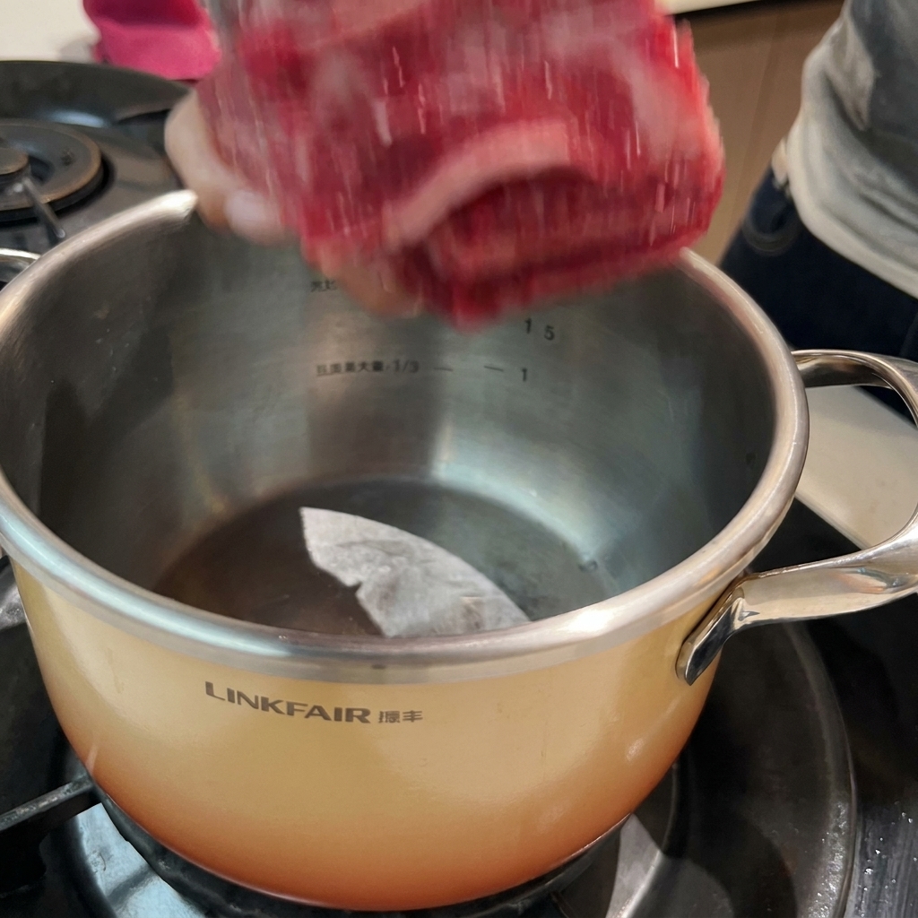 Côtes de bœuf trempant dans une casserole deau froide avec des aromates, prêtes pour le processus de blanchiment.