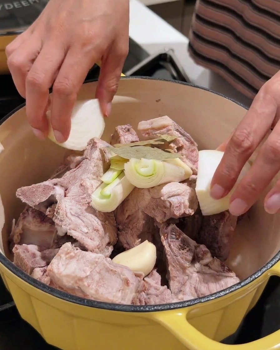 Divers aromates dont lail, loignon et la pâte de soja ajoutés dans la marmite avec le porc.