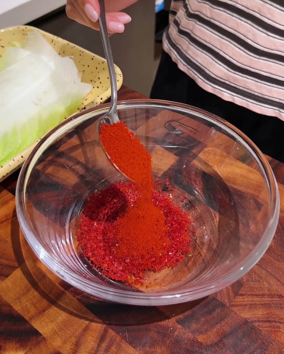 Poudre de piment rouge versée dans un bol en verre avec dautres épices.