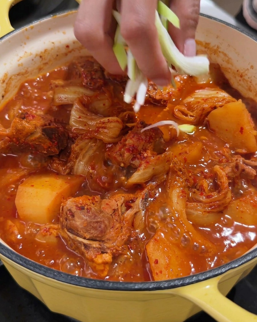 Une marmite de soupe épicée au porc garnie doignons nouveaux frais.