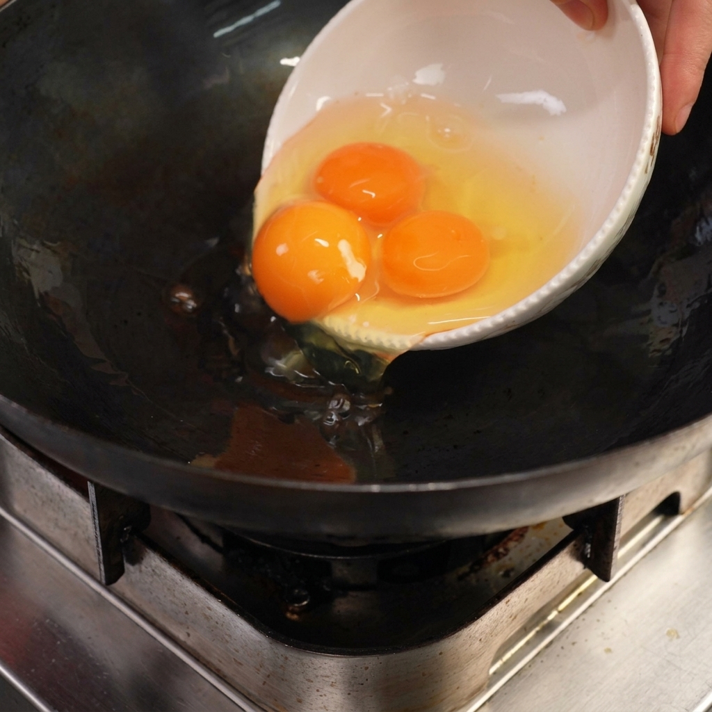 Œufs grésillant dans un wok avec du saindoux chaud.