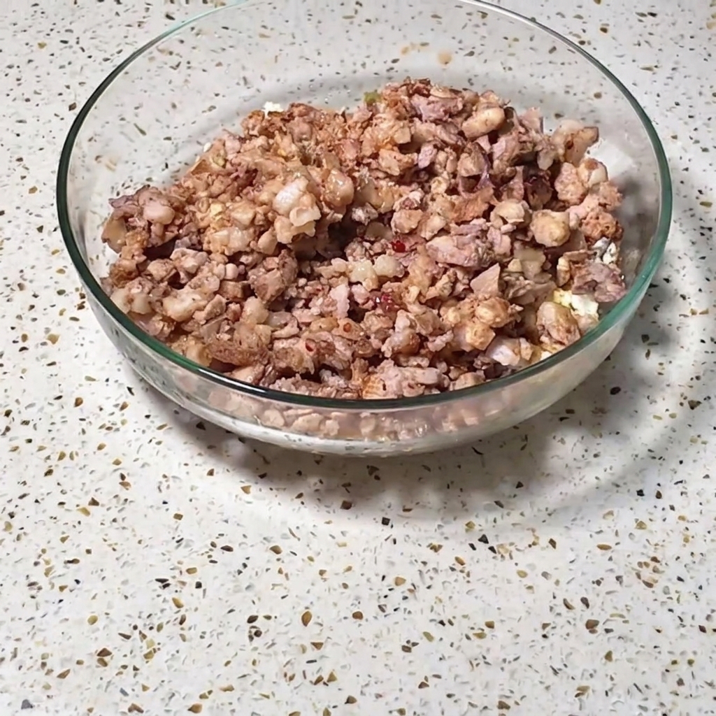 Un grand bol en verre rempli dun mélange de viandes hachées, dœufs et de légumes assaisonnés sur un comptoir.