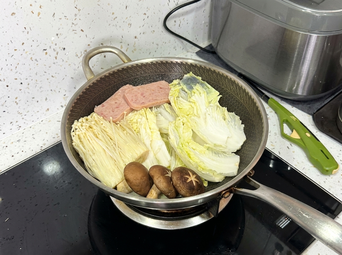Un wok entièrement garni contenant du chou napa, des champignons enoki, des champignons shiitake, de la viande de luncheon et des tranches de porc.