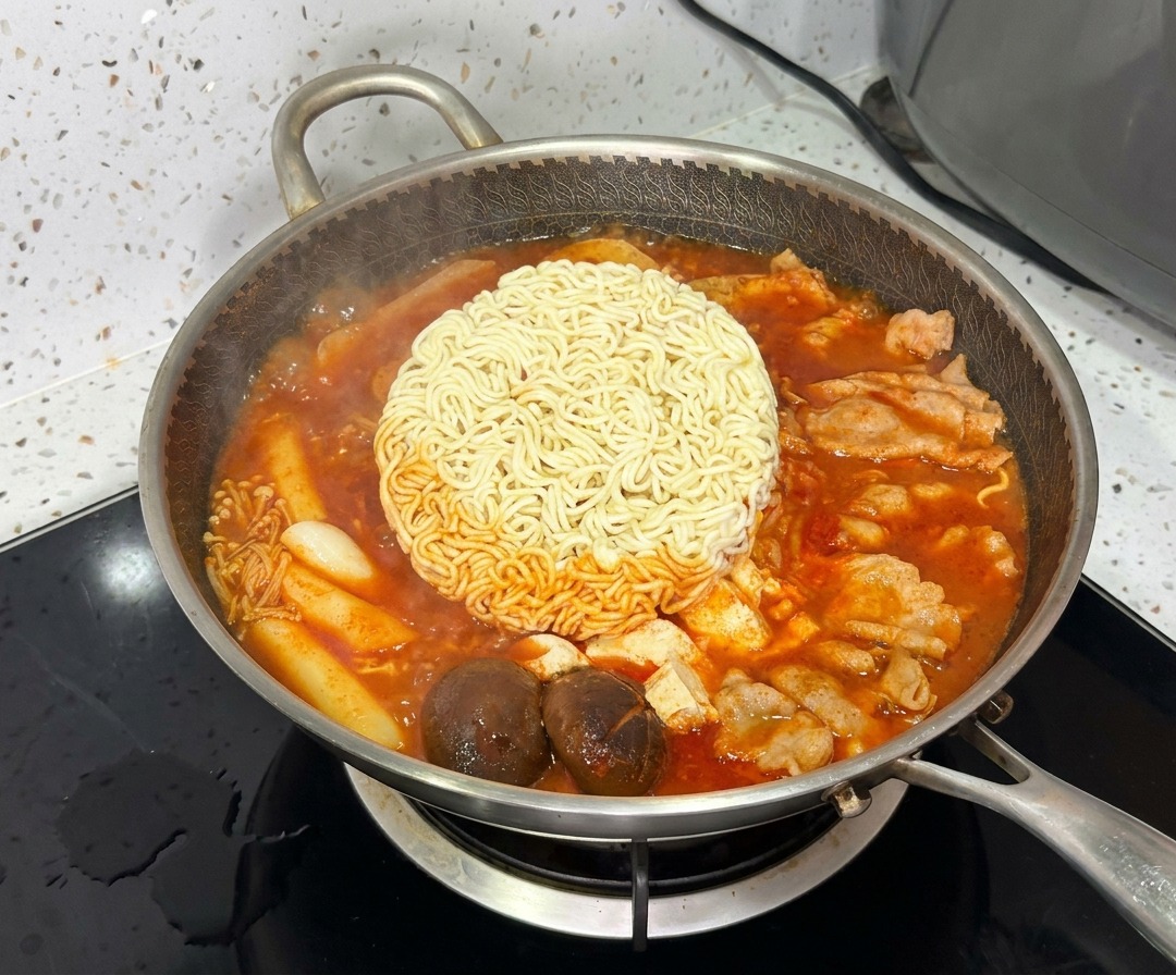 Un bloc de nouilles ramen cuisant au centre du ragoût de larmée coréenne vibrant et frémissant.