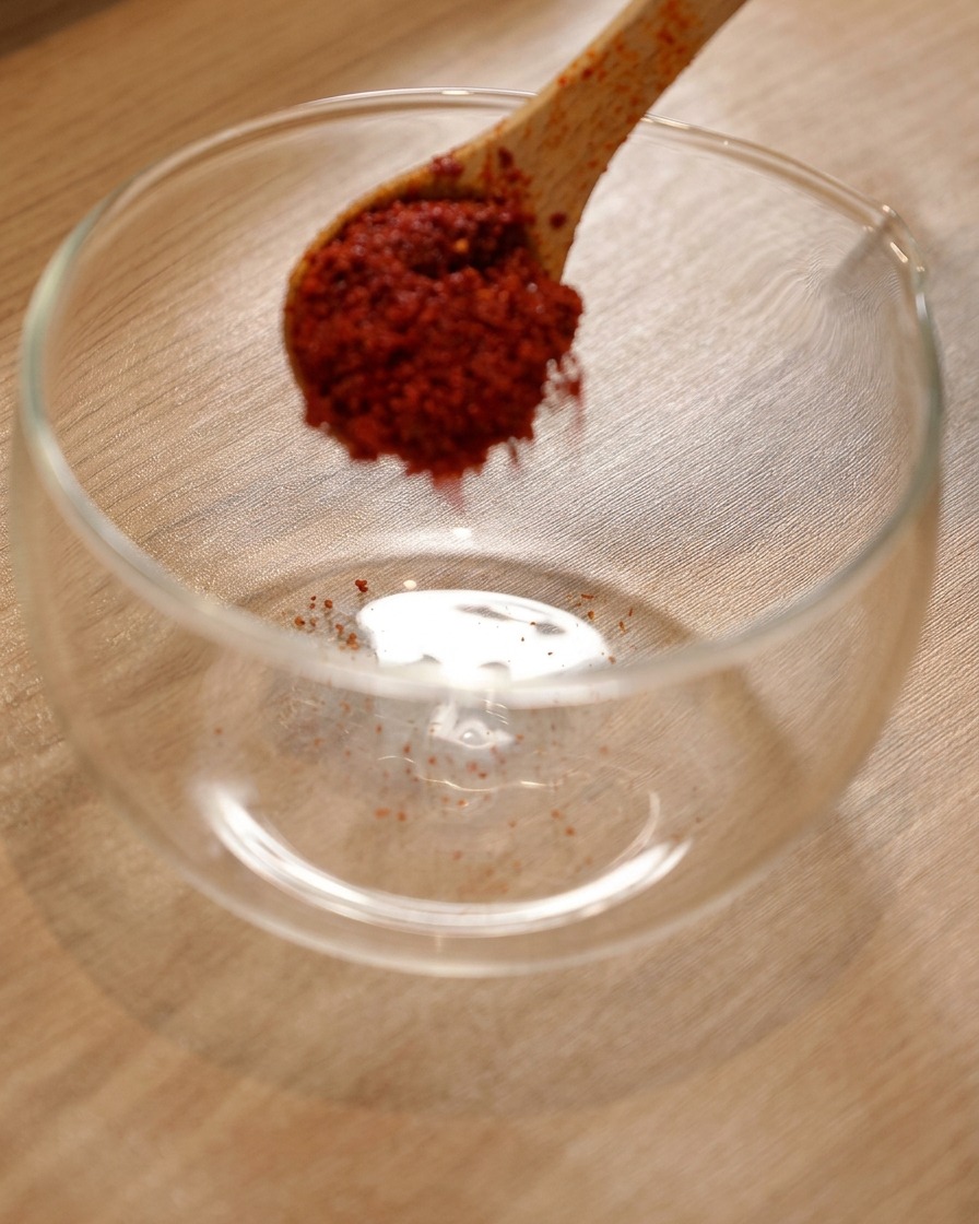 Piment en poudre dans un bol en verre avec de la sauce piquante coréenne et de la sauce soja claire ajoutées.