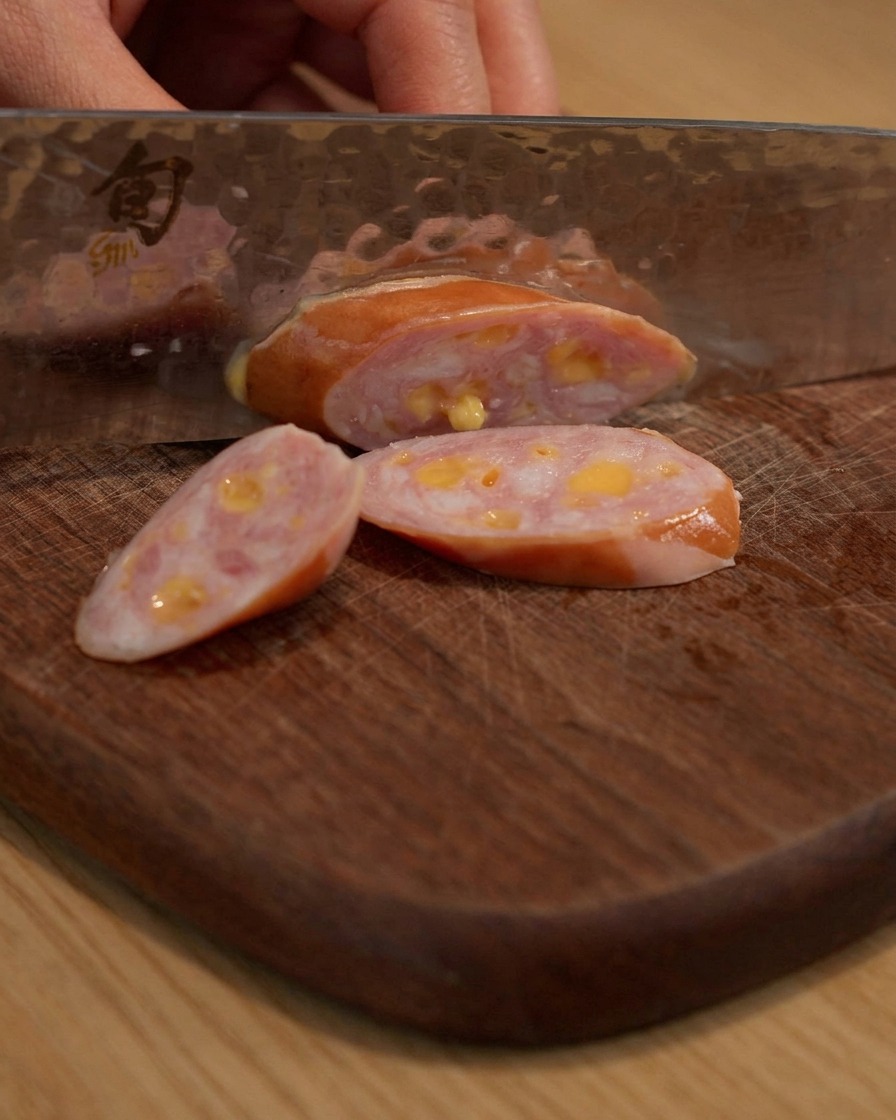 Saucisse tranchée sur une planche à découper en bois.