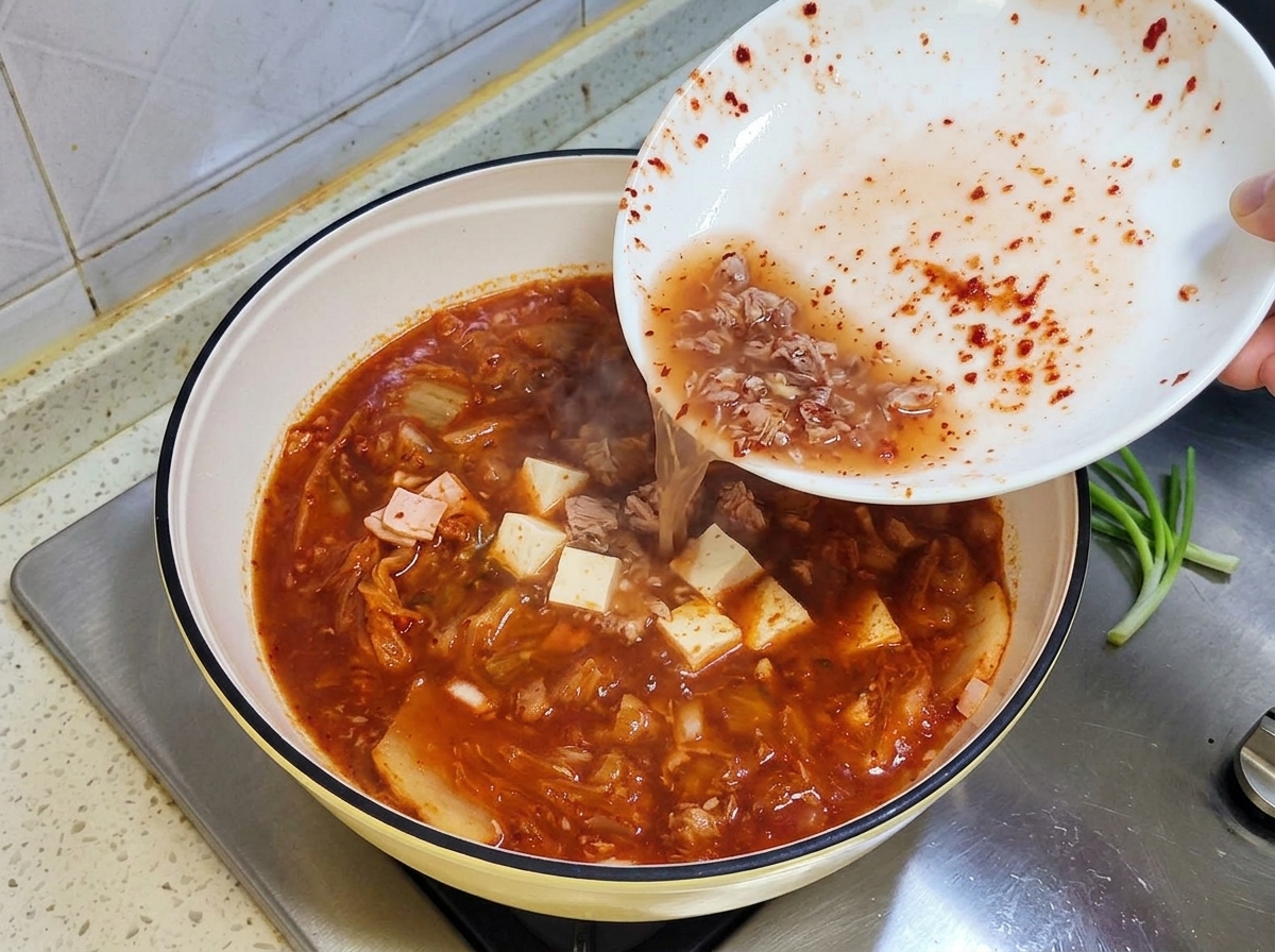 De leau et du liquide dassaisonnement résiduel versés dun bol blanc dans la casserole de ragoût mijotant.