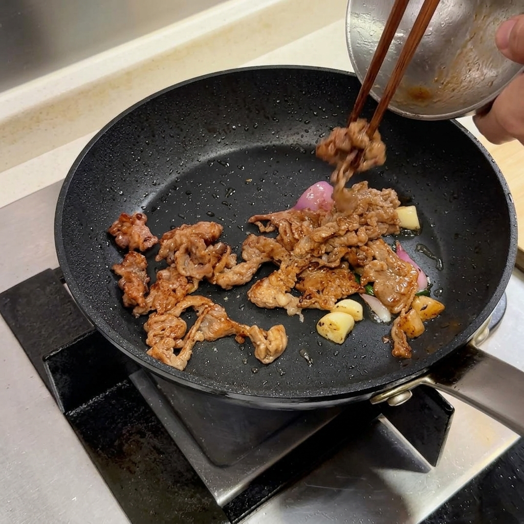 Tranches de bœuf et aromates dans une poêle accompagnés dune noix de beurre en cours dincorporation.