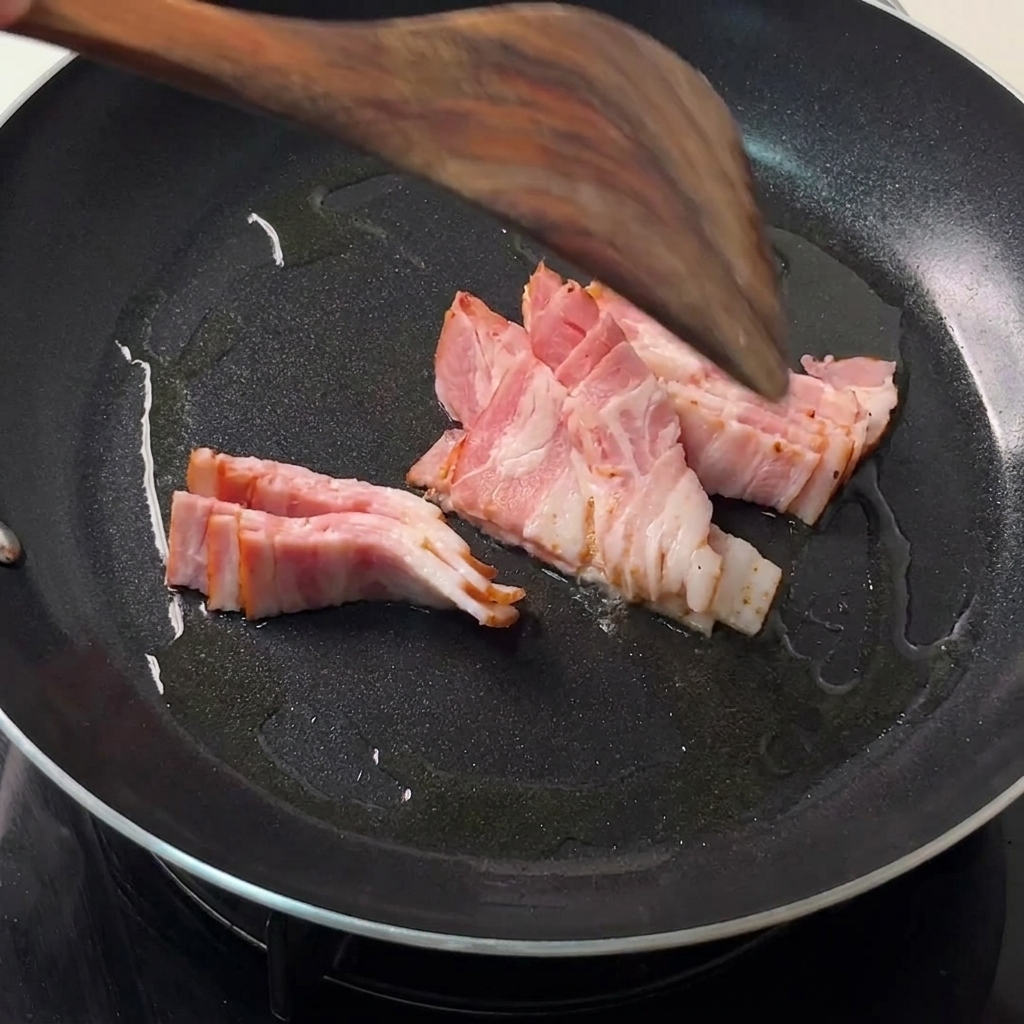 Tranches de bacon en train de frire dans une poêle noire chaude avec une spatule en bois qui les retourne.