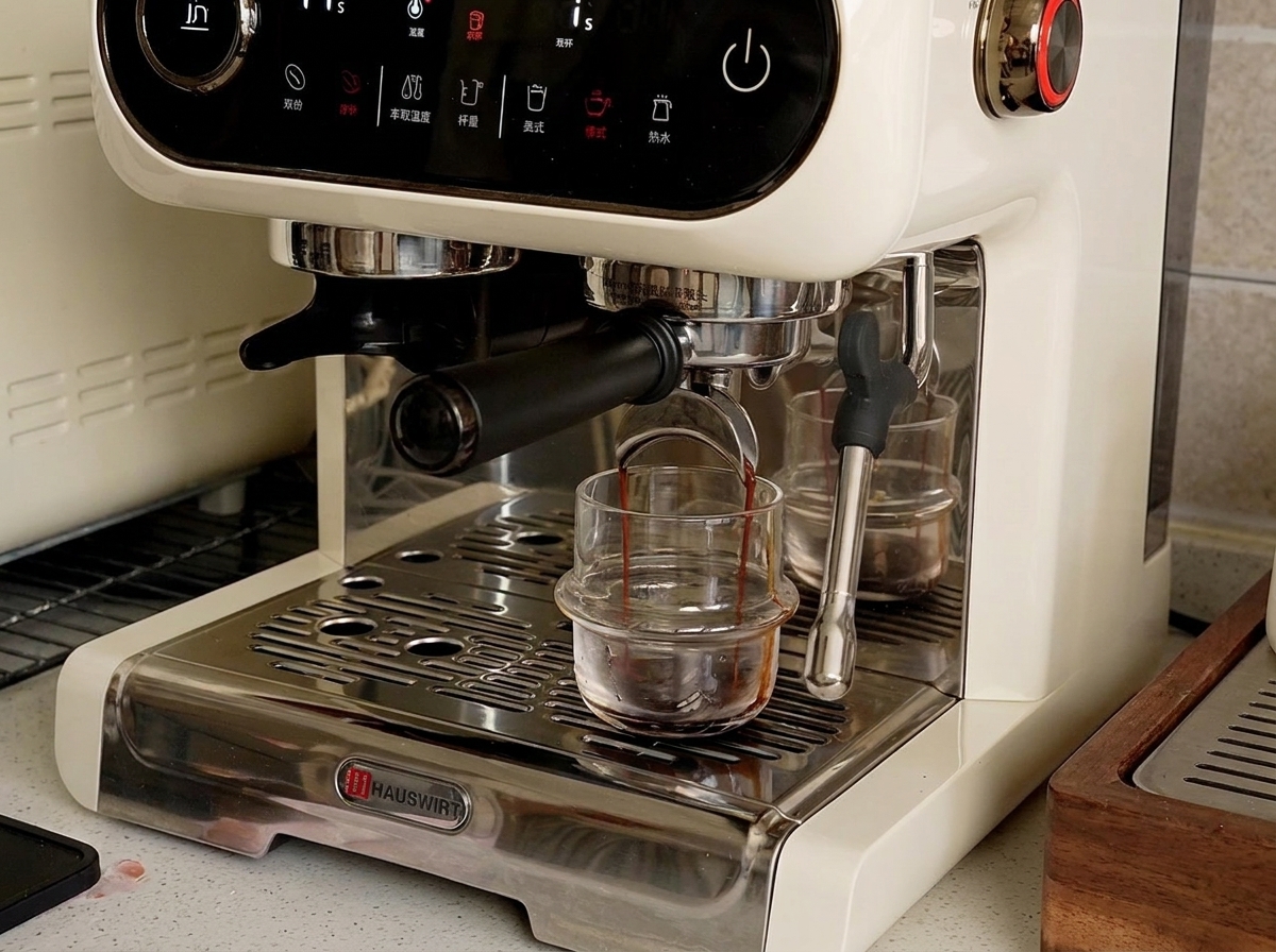 Une machine à expresso versant un expresso liquide et sombre dans une petite tasse en verre sur le bac dégouttage.