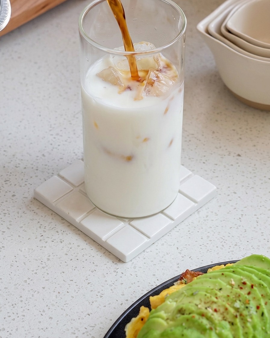 De lexpresso frais versé dans un verre de lait glacé, créant un motif de dégradé tourbillonnant.