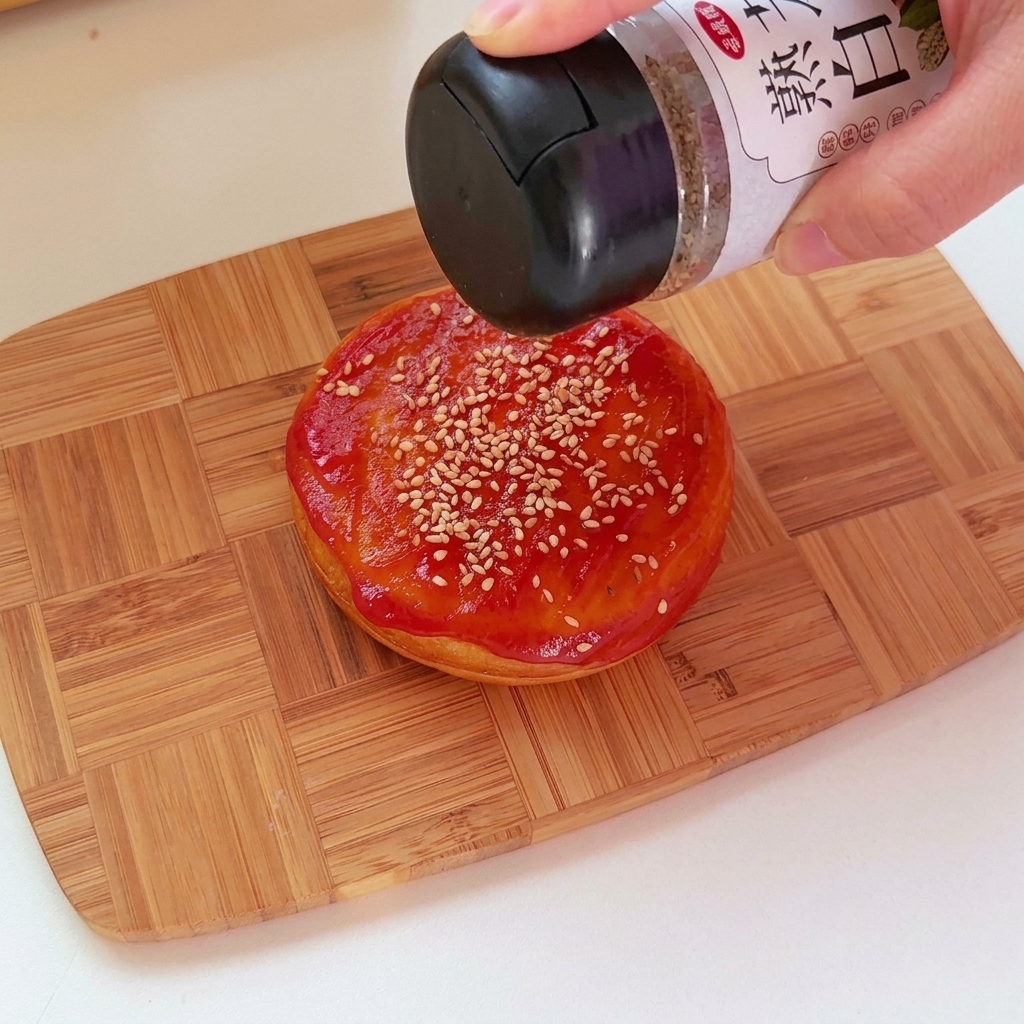 Gros plan de ketchup appliqué sur le dessus dun pain rond salé avec des graines de sésame.