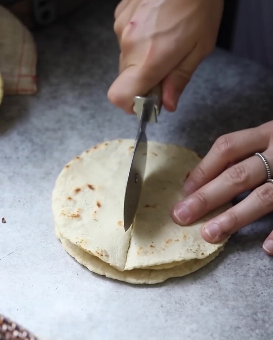 Des pains plats de tortilla cuits et empilés coupés en sections triangulaires avec une lame.