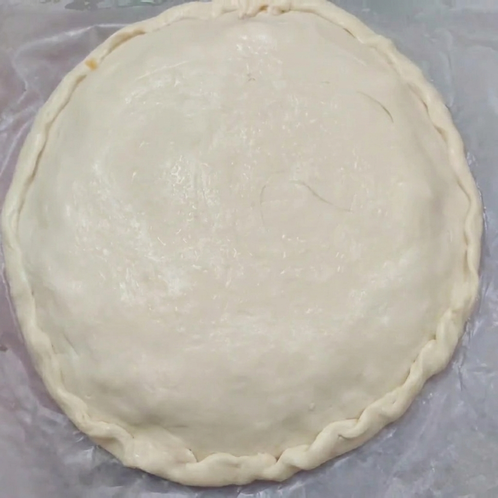 Gros plan sur une tourte crue aux bords joliment pincés qui scellent les pâtes du haut et du bas ensemble.