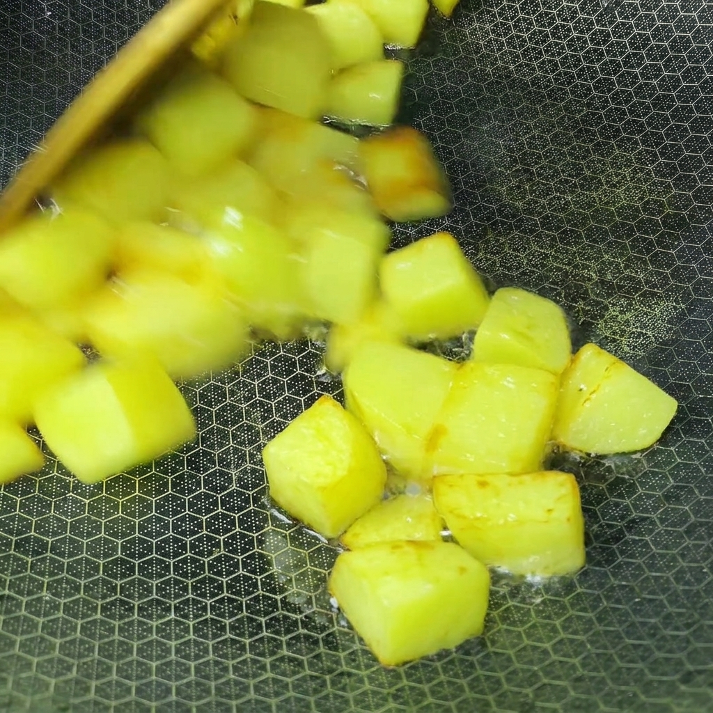Cubes de pommes de terre frisant dans lhuile à lintérieur dun wok jusquà devenir dorés.