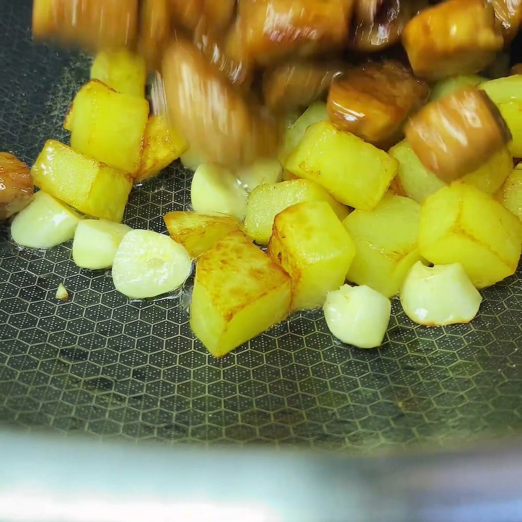 Pommes de terre et porc cuits mélangés ensemble dans un wok.