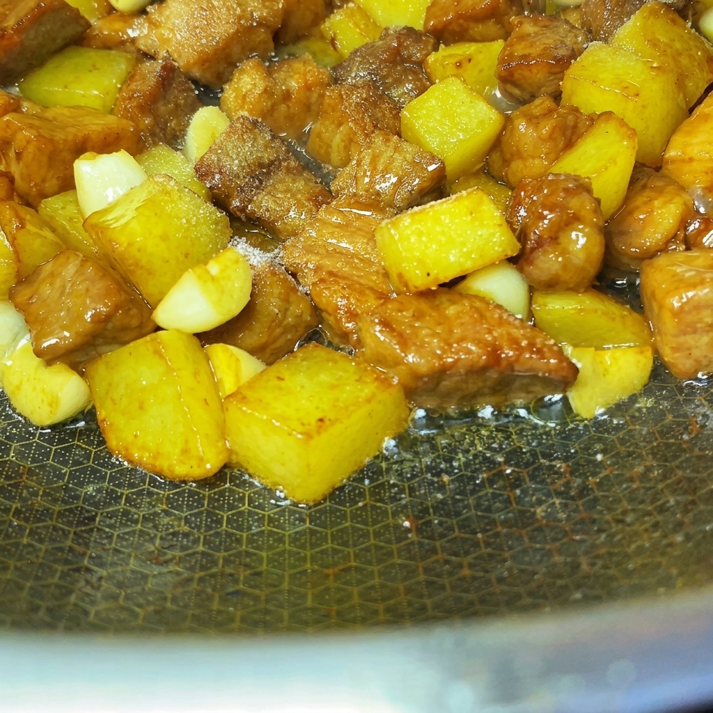 Épices et graines de sésame saupoudrées uniformément sur le porc et les pommes de terre poêlés.