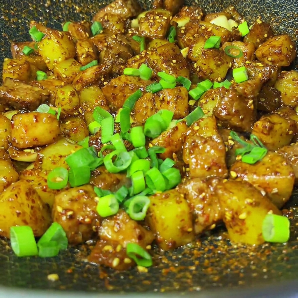 Cébette fraîchement ciselée parsemée sur le plat de porc au cumin et pommes de terre dans un wok.